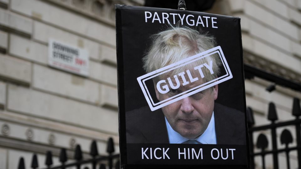 Cartas de manifestante em Downing Street contra o primeiro-ministro Boris Johnson. A placa diz "partygate", "culpado" (sobre a foto do rosto de Johnson) e "expulsem-no aos chutes".