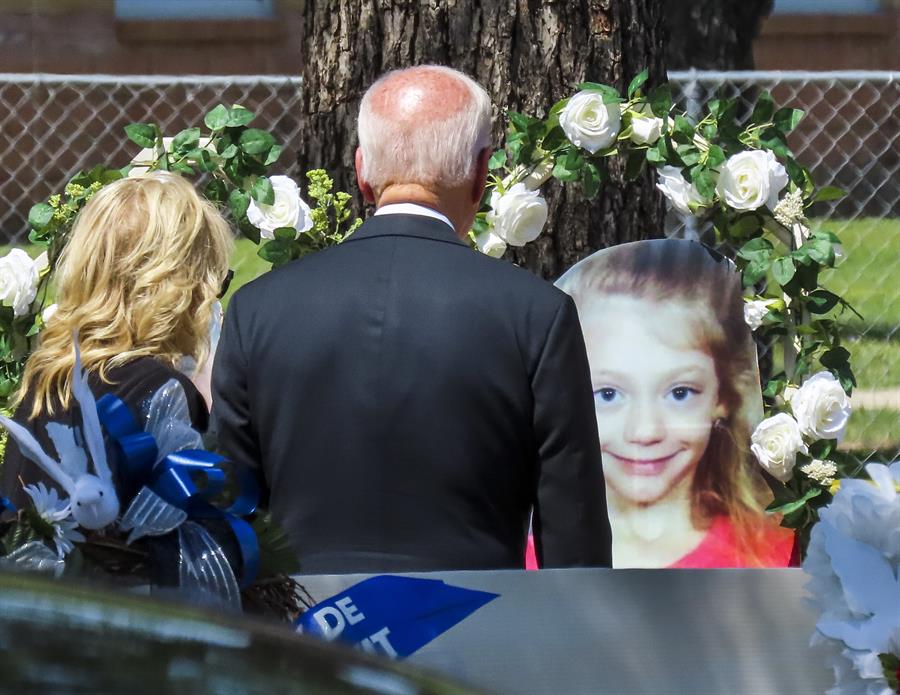 Jill Biden e Joe Biden, de costas, observam foto de menina cercada por coroas de flores na frente da escola em que ela, dezoito outras crianças e duas professoras foram mortas por um atirador no dia 24.