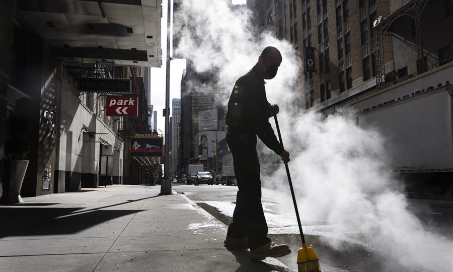 Os danos provocados pelos lockdowns Funcionário varre calçada de hotel perto da Times Square praticamente vazia, na região de alguns teatros da Broadway, em março do ano passado: lockdown levou ao cancelamento de shows um ano antes