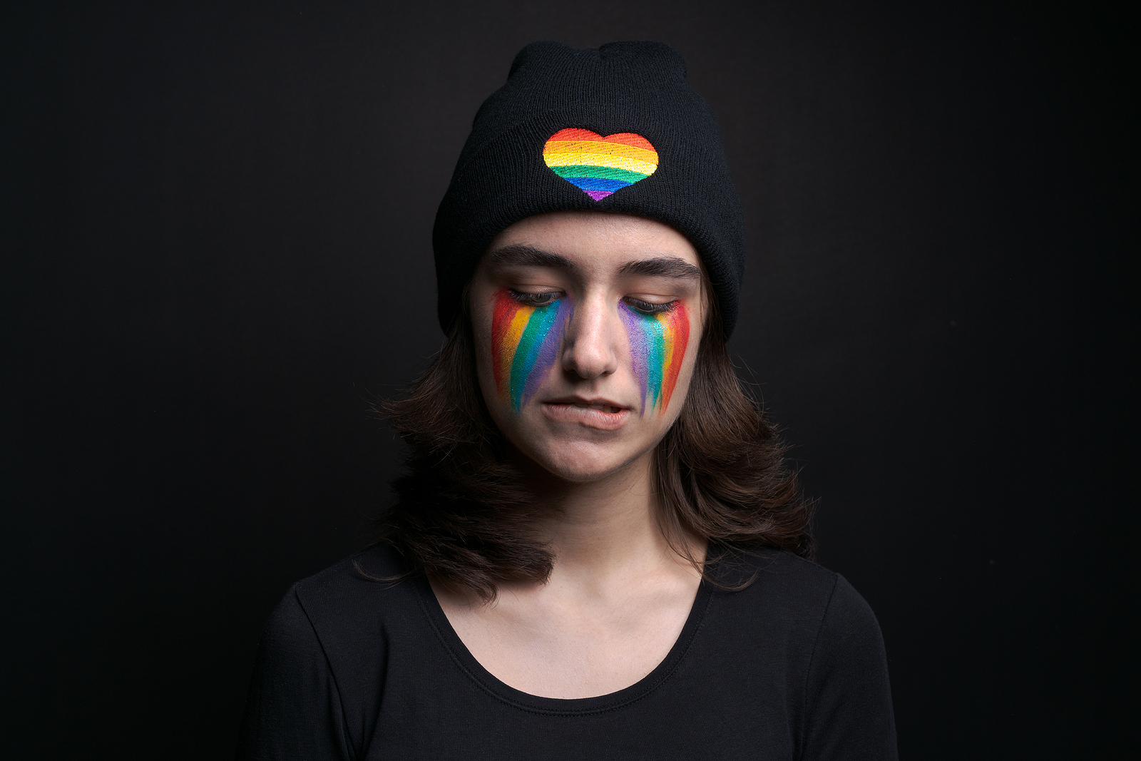 Garota com pintura facial sugerindo lágrimas de arco-íris, símbolo LGBT