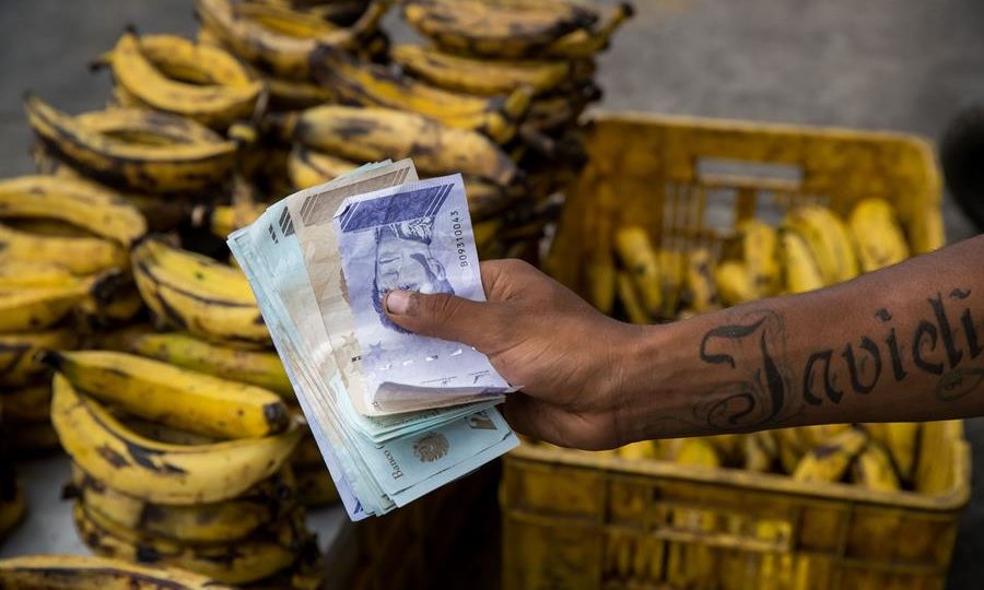 Ambulante segurando notas de bolívar, em Caracas, em fevereiro: moeda sofreu corte de 14 zeros desde 2008