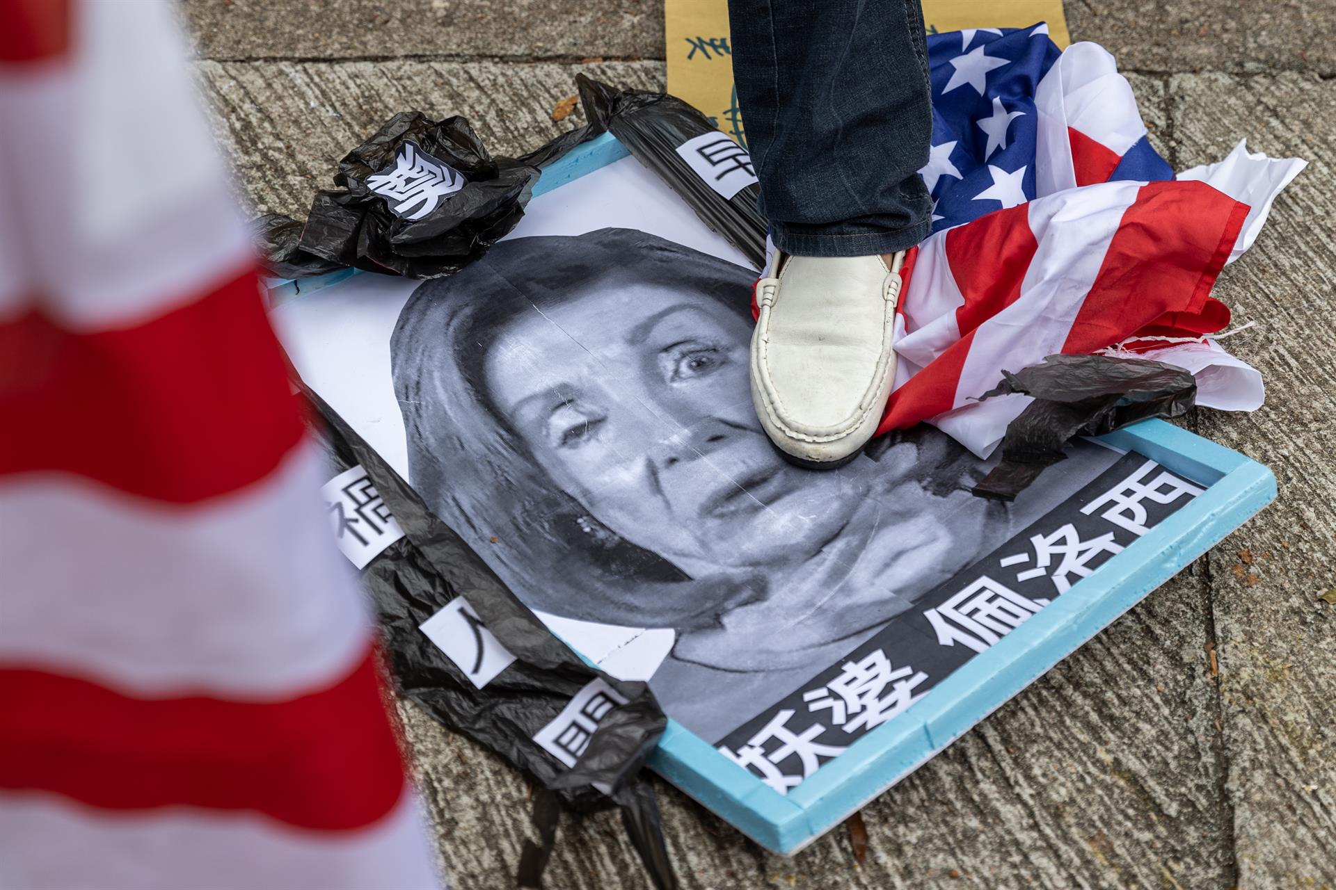 Grupo de manifestantes pró-China pisa em uma foto da presidente da Câmara dos Deputados dos EUA, Nancy Pelosi, em frente ao Consulado Geral dos Estados Unidos em Hong Kong, China, 3 de agosto de 2022.