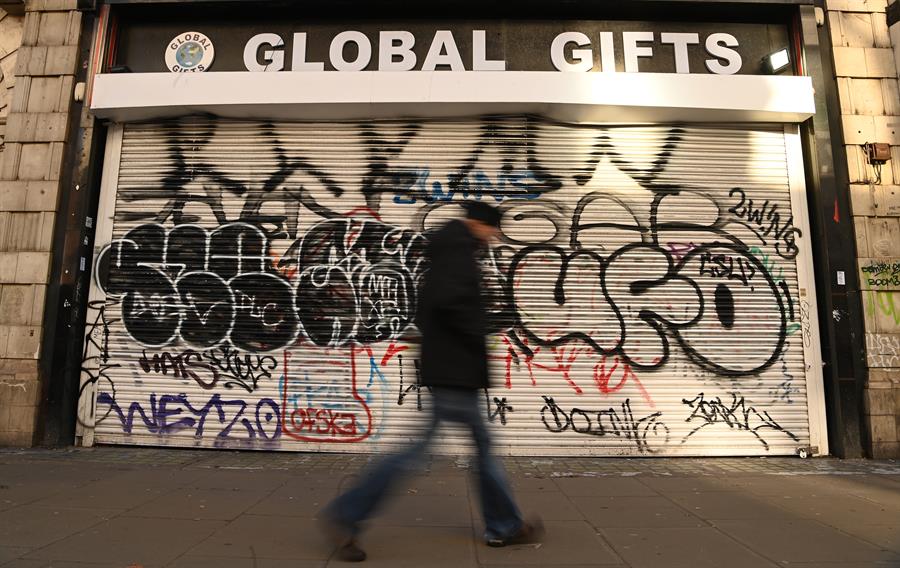 Pedestre em frente a uma loja fechada em Londres, neste mês