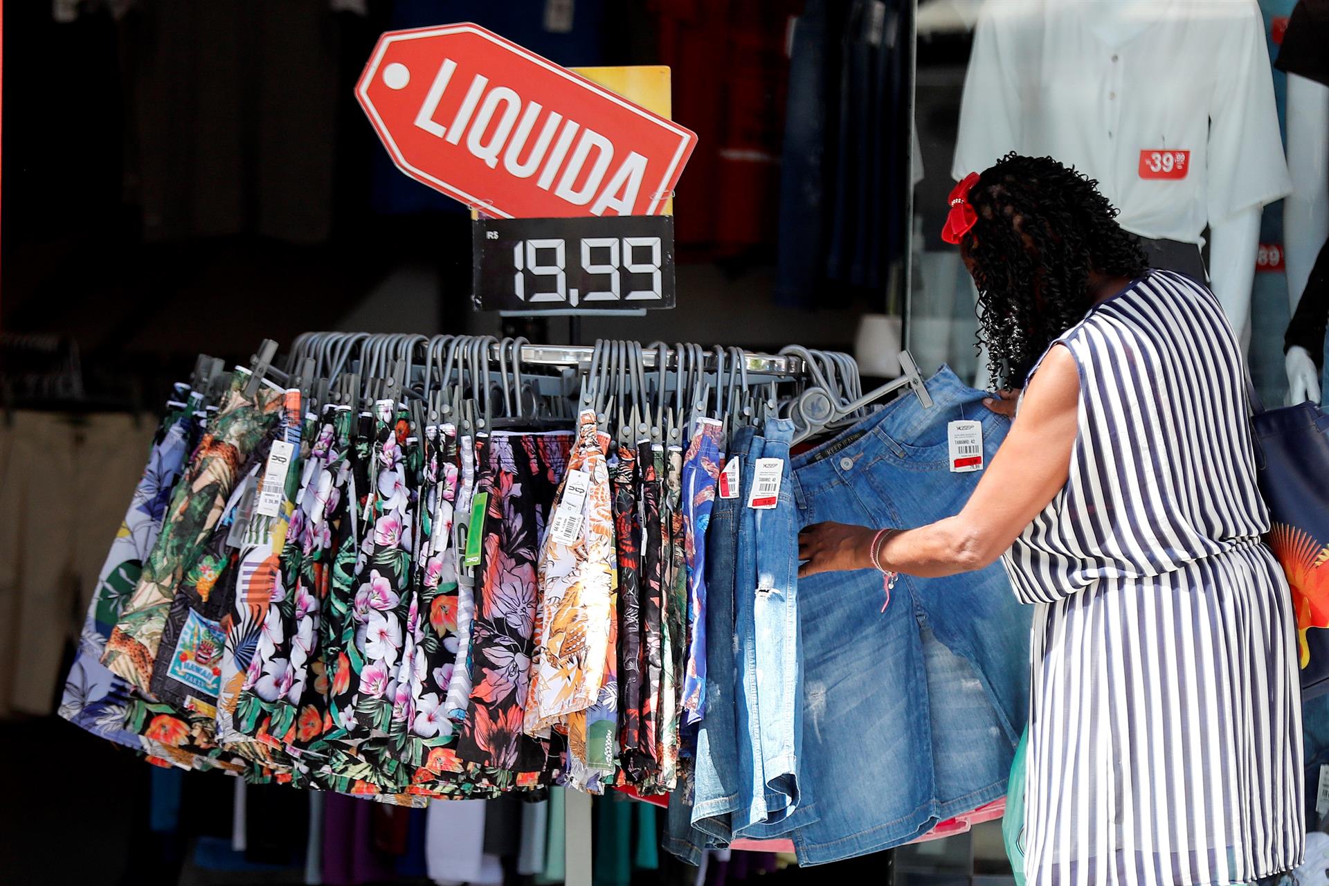 Mulher escolhe roupa em loja