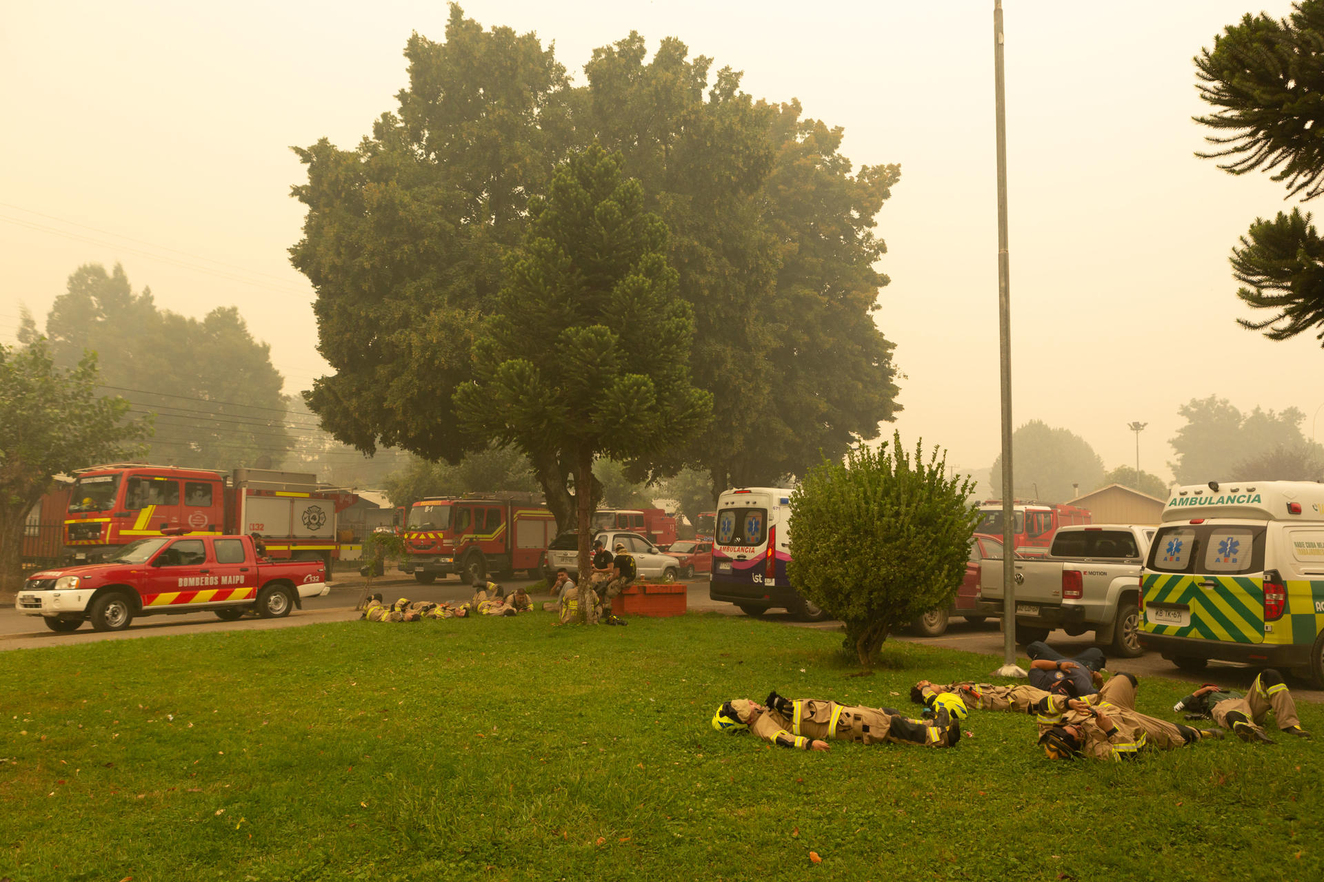 Bombeiros descansam em gramado após passar a noite combatendo incêndio florestal no Chile que deixou centenas de desabrigados e fez dezenas de vítimas. Santa Juana. região de Biobío.
