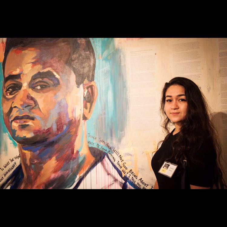 Jewher Ilham ao lado de uma ilustração do pai, o economista Ilham Tohti, preso pelo Partido Comunista Chinês há dez anos