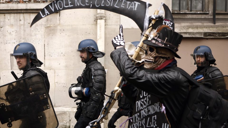 Policiais franceses passam por um manifestante carregando uma foice com os dizeres 'violência é o Estado' enquanto milhares de pessoas participam de uma nova manifestação contra a reforma da previdência em Paris, França, 15 de março de 2023.