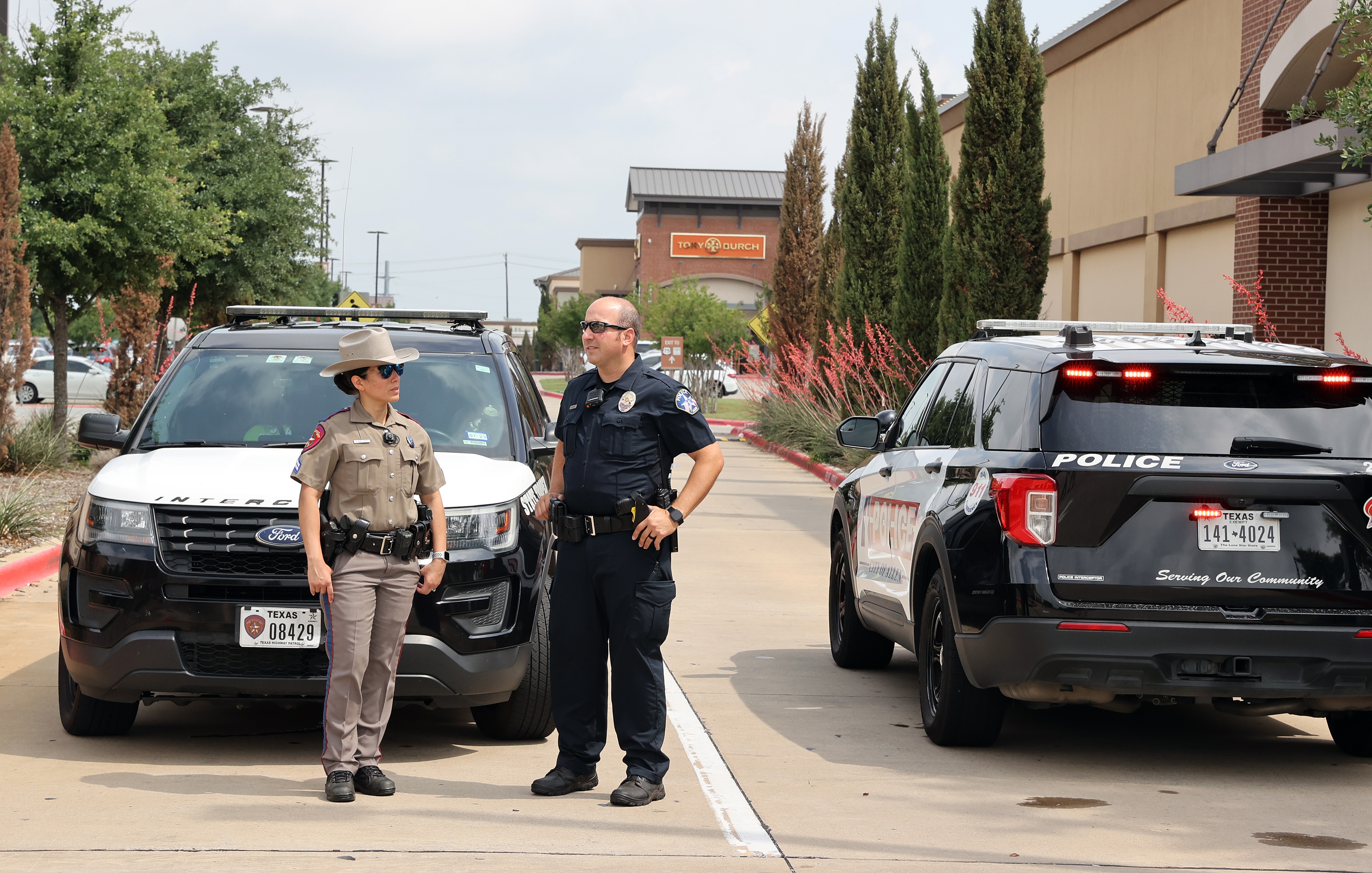 Um policial estadual (L) e um policial da cidade de Allen (R) conversam enquanto bloqueiam a entrada do Allen Premium Outlet Mall devido a um tiroteio em massa ocorrido no dia anterior em Allen, Texas.