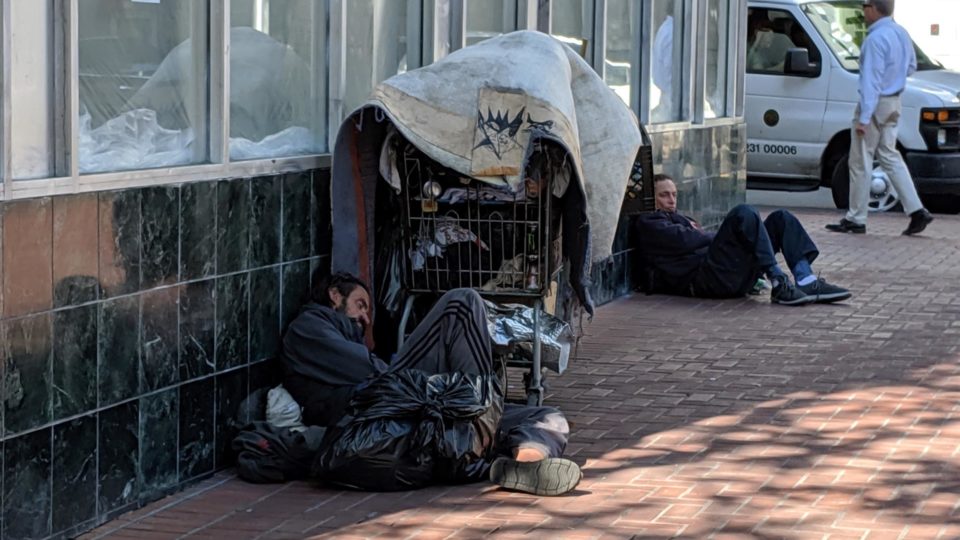 Sem-teto deitado ao lado de seus pertences em uma rua no bairro Tenderloin em San Francisco, Califórnia, em 2020