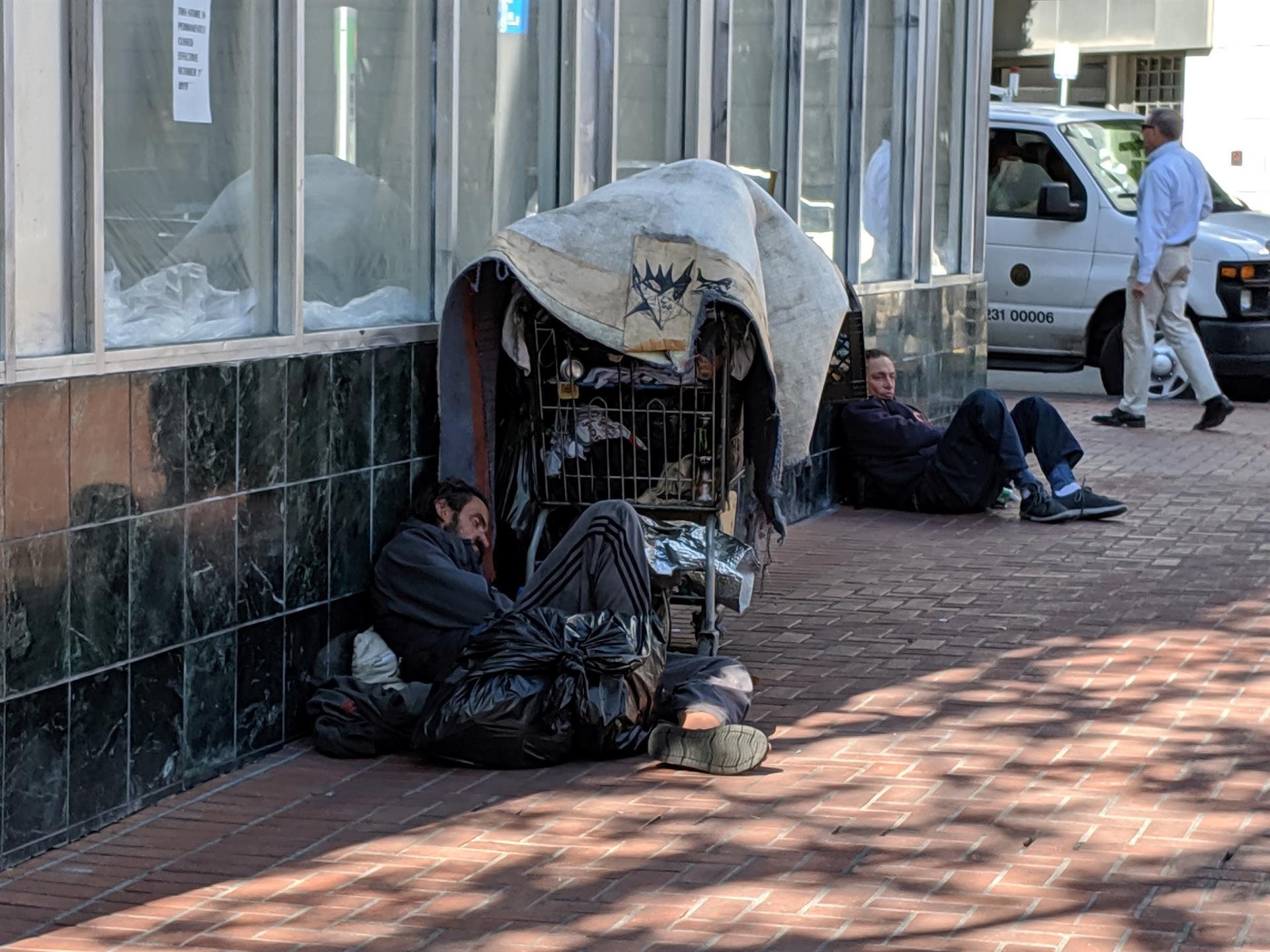 Sem-teto deitado ao lado de seus pertences em uma rua no bairro Tenderloin em San Francisco, Califórnia, em 2020