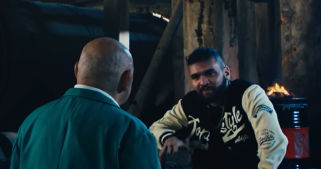 No teaser de seu especial de humor, Tiago Santineli ordena a mortre, a pauladas, de um personagem sósia de Luciano Hang.