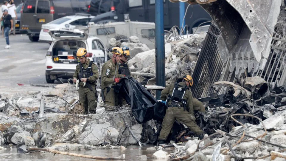 Forças de segurança israelenses removem um corpo do lado de fora de uma delegacia de polícia destruída que era controlada pelo Hamas na cidade de Sderot, no sul, perto da fronteira com Gaza