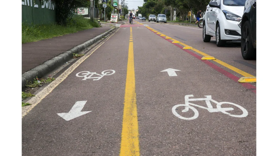 Ciclofaixa em rua de Curitiba com um ciclista ao fundo