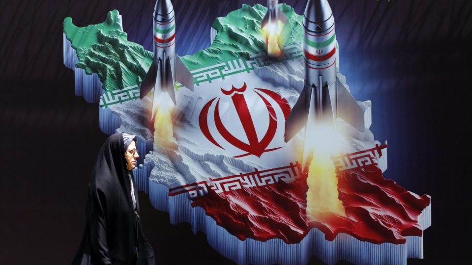 Uma mulher iraniana passa por um cartaz anti-israelense com imagens de mísseis iranianos, em Teerã, 16 de abril de 2024.