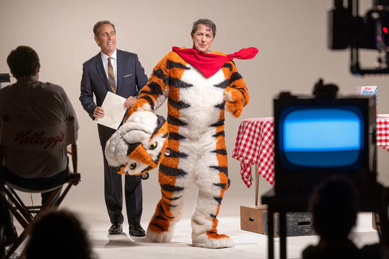 Jerry Seinfeld em cena com Hugh Grant, vestindo a roupa do mascote Tony the Tiger, no filme da Netflix