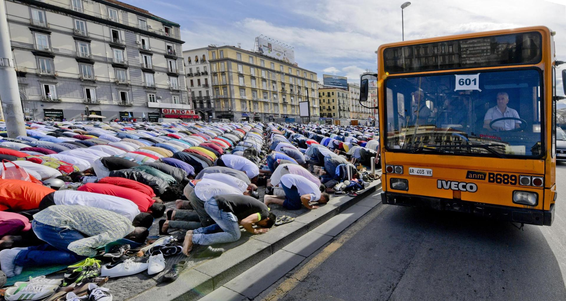 Um ônibus passa enquanto muçulmanos rezam para celebrar o Eid al-Fitr (celebração que marca o fim do jejum do Ramadã), na praça Garibaldi, em Nápoles, sul da Itália, em 15 de junho de 2018.