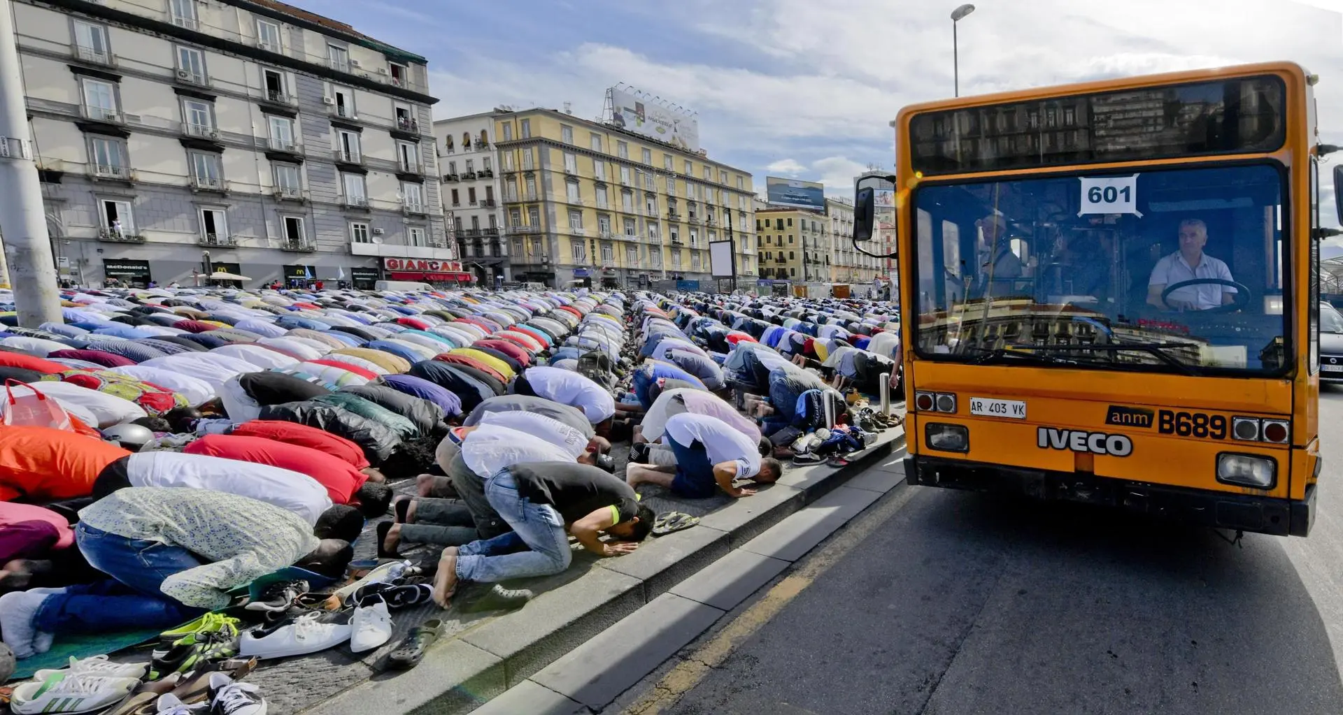 Um ônibus passa enquanto muçulmanos rezam para celebrar o Eid al-Fitr (celebração que marca o fim do jejum do Ramadã), na praça Garibaldi, em Nápoles, sul da Itália, em 15 de junho de 2018.