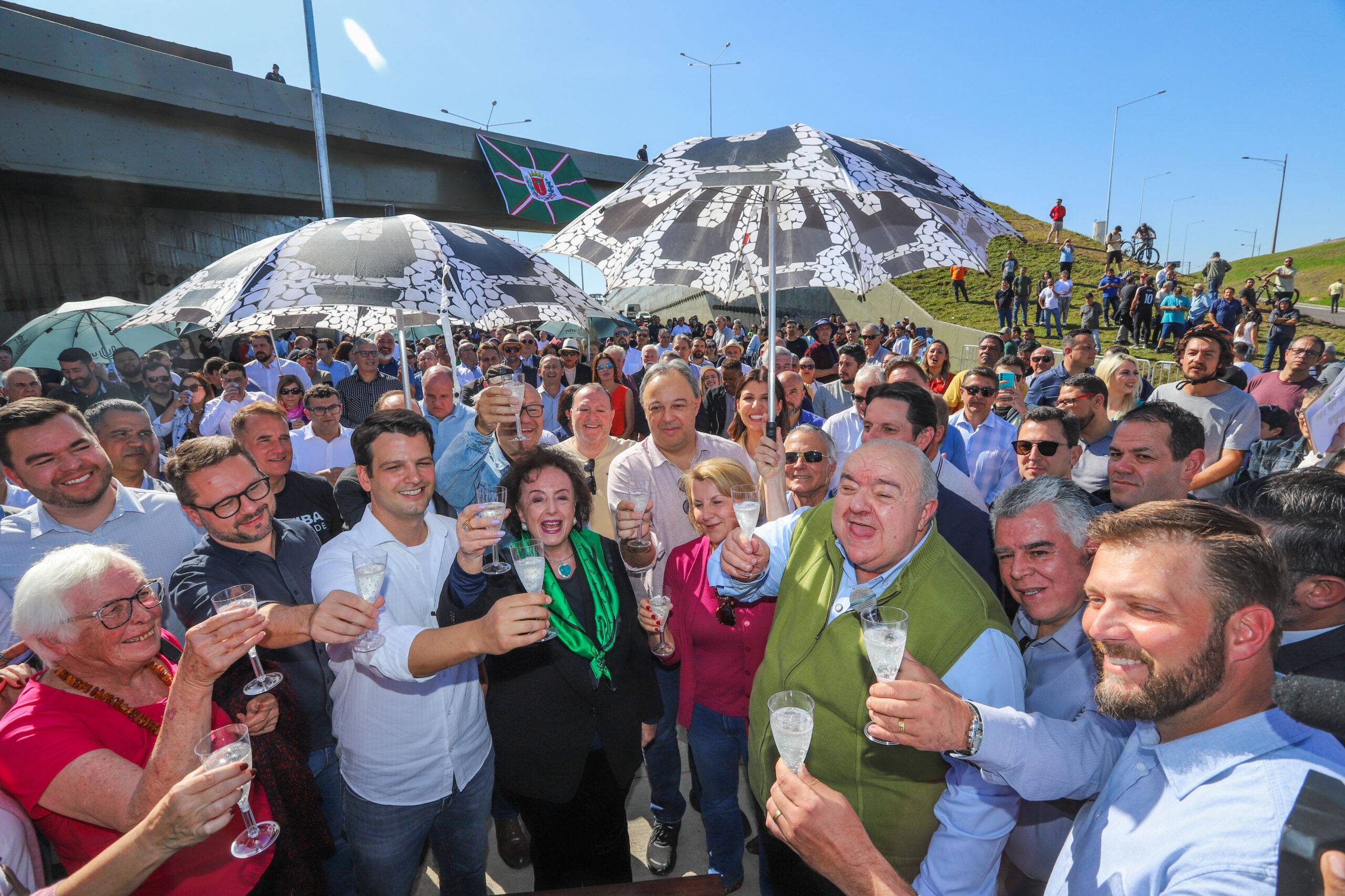 Antecipada pelo calendário eleitoral, Greca inaugura Linha Verde ao lado do pré-candidato Eduardo Pimentel (PSD), com brindes de comemoração.