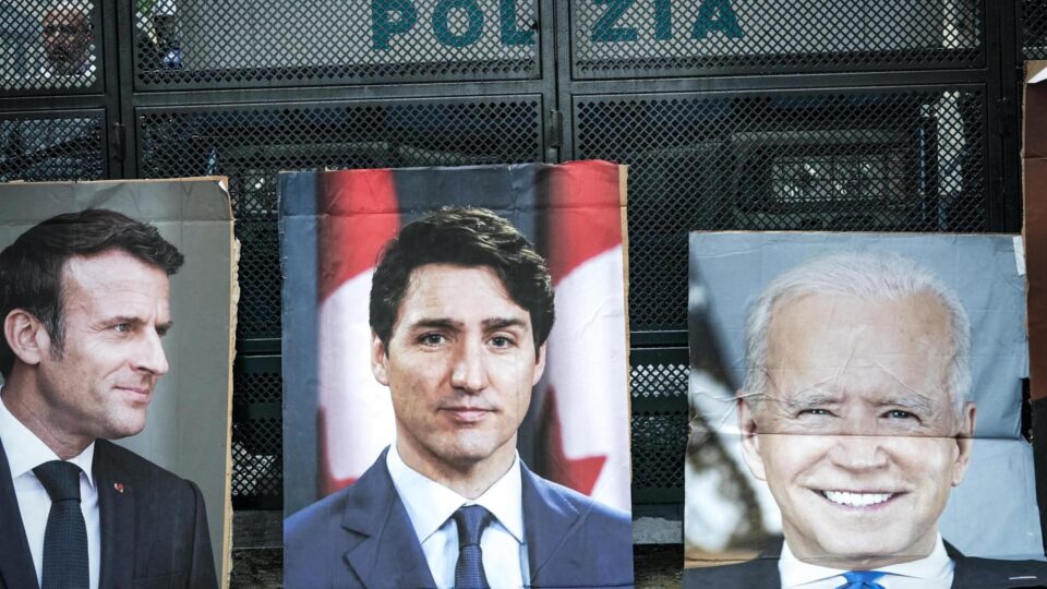 Fotos de líderes mundiais, incluindo (da esquerda para a direita) o presidente francês, Emmanuel Macron, o primeiro-ministro canadense, Justin Trudeau, e o presidente dos EUA, Joe Biden, durante um protesto contra a cúpula do G7 sobre Energia e Meio Ambiente em Venaria Reale, perto de Turim, Itália, em 28 de abril de 2024.