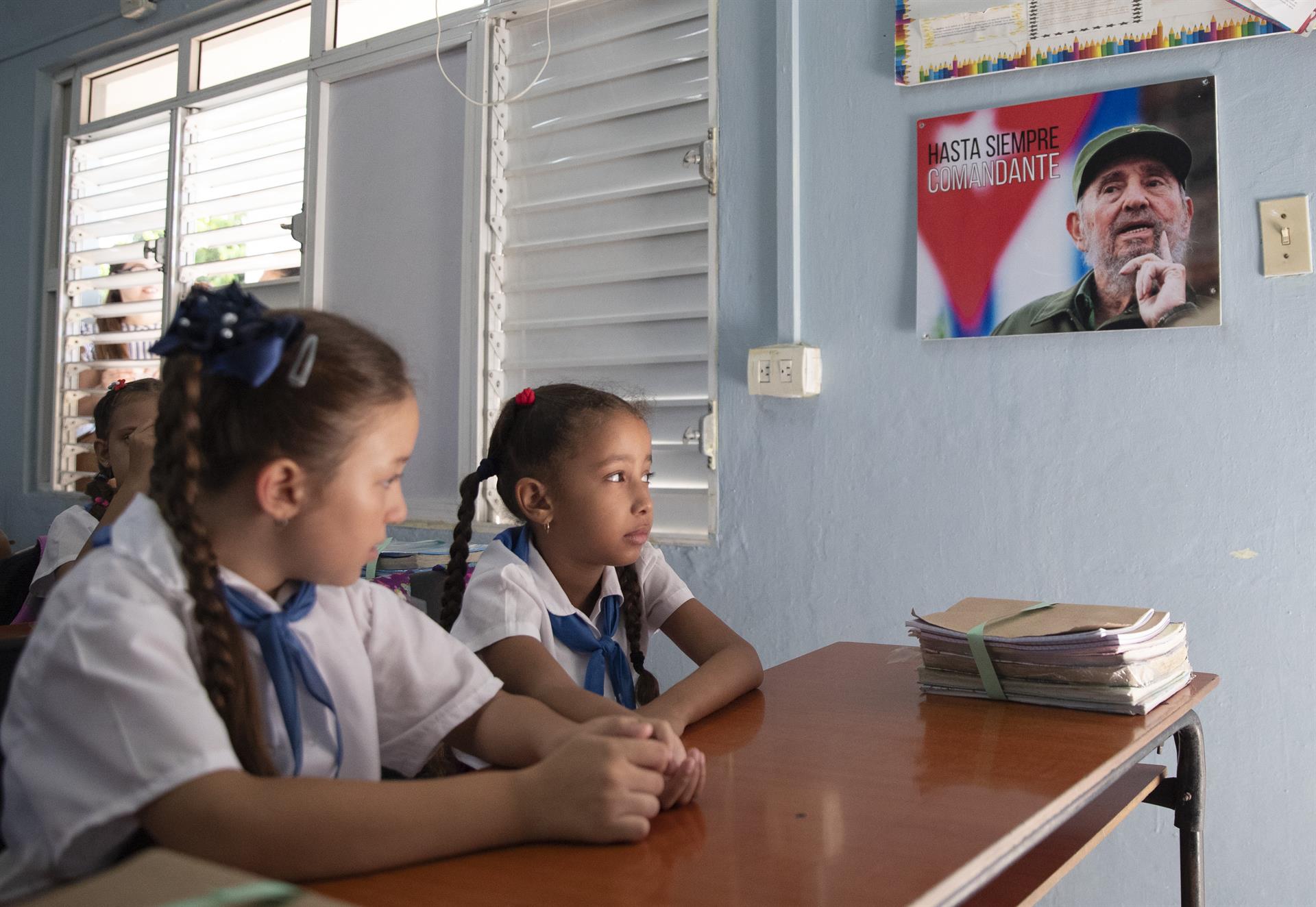 Meninas assistem às aulas ao lado de uma foto do ditador Fidel Castro, durante o primeiro dia do ano letivo na escola primária Vo Thi Thang, em 2023, em Havana (Cuba)