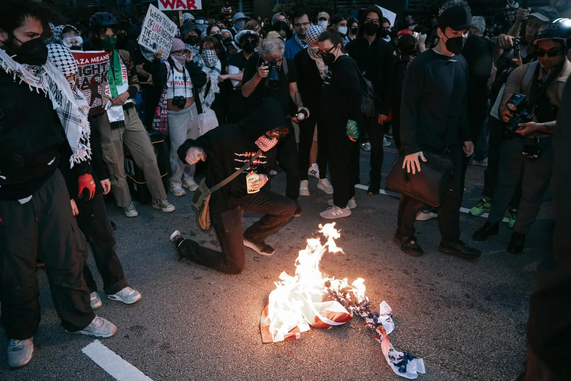 Manifestantes queimam uma bandeira dos EUA durante protesto contra as ações militares de Israel em Gaza, do lado de fora do consulado de Israel, durante o segundo dia da Convenção Nacional Democrata (DNC) em Chicago, Illinois, EUA, 20 de agosto de 2024