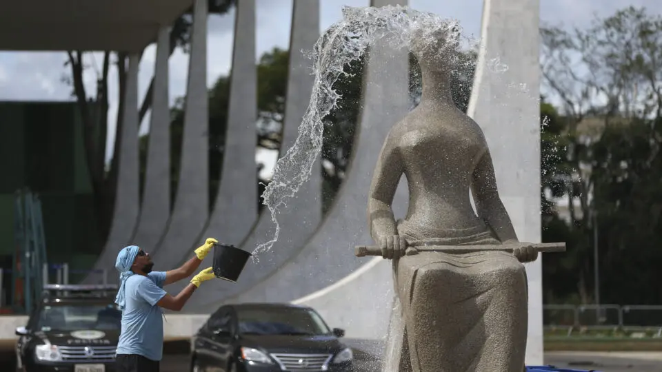 Funcionário lava estátua da Justiça em frente ao STF em janeiro de 2023