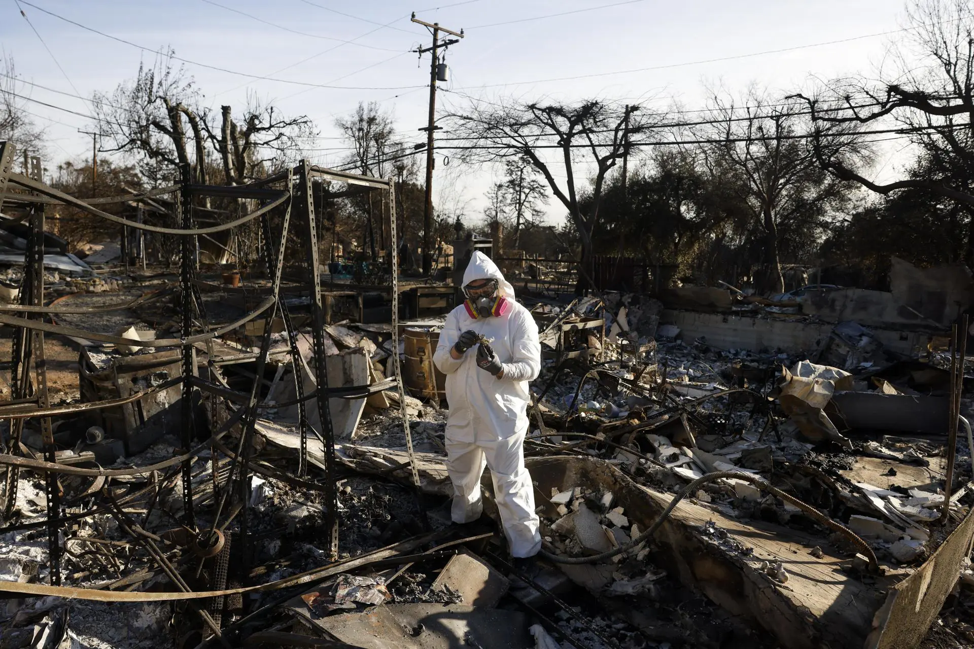 Uma pessoa usando equipamento de proteção vasculha os escombros de sua casa, que foi queimada no incêndio de Eaton, em Altadena, Califórnia, EUA, em 21 de janeiro de 2025.