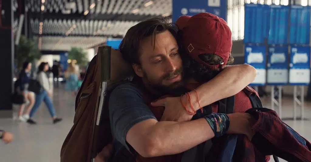 Benji (Kieran Culkin) abraça o primo David (Jesse Eisenberg) ao retornarem da Polônia