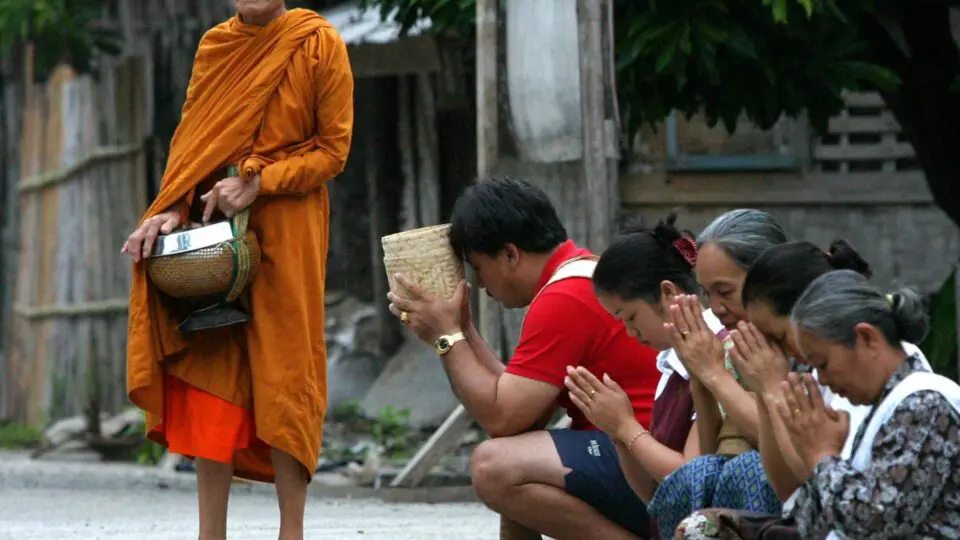 Um monge faz orações por alguns moradores de Luang Prabang depois que eles deram comida a alguns dos 800 monges da cidade, logo após o nascer do sol, 13 de setembro de 2003. Antiga capital real do Laos, Luang Prabang é o maior cartão de visita turístico para o Laos. A cidade foi declarada patrimônio mundial da UNESCO em 1995.