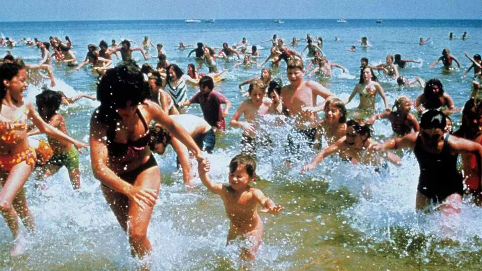 Os figurantes se pirulitam da praia para escapar do tubarão