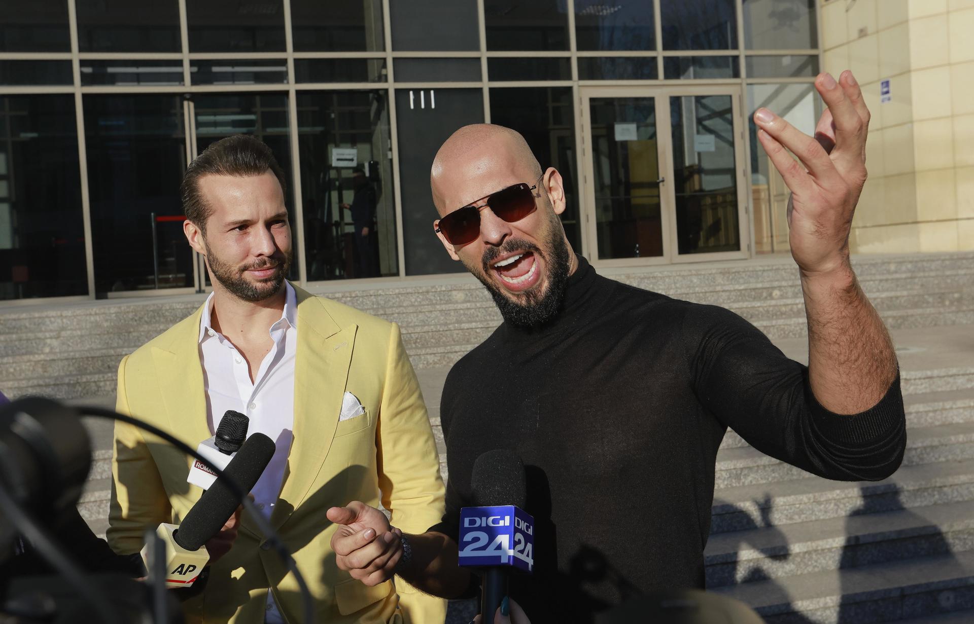 O ex-kickboxer profissional e influenciador de mídia social Andrew Tate (à direita), apoiado por seu irmão Tristan (à esquerda), gesticula após uma audiência sobre devolução de bens confiscados em Bucareste, Romênia, 09 de janeiro de 2025.