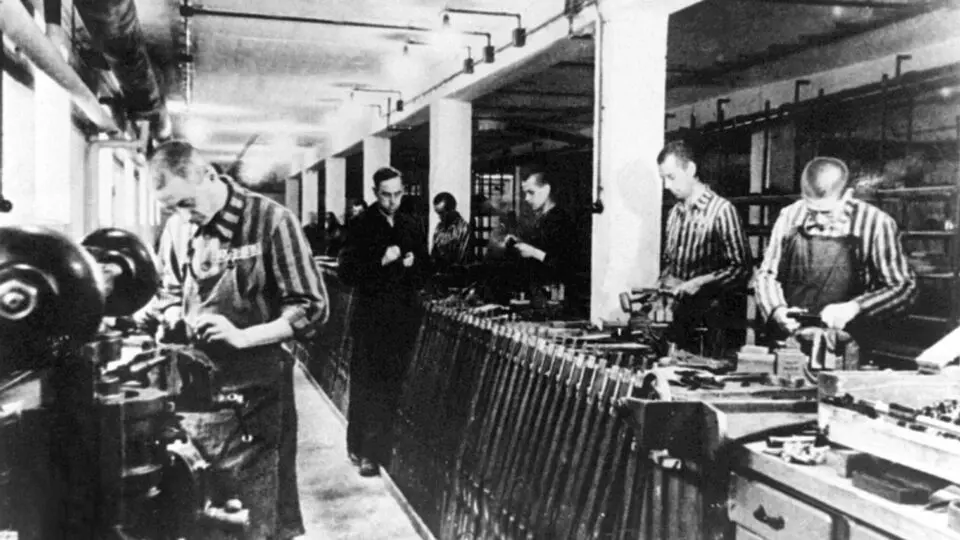 Foto de arquivo sem data mostrando um trabalhador escravizado produzindo armas no campo de concentração nazista em Dachau.