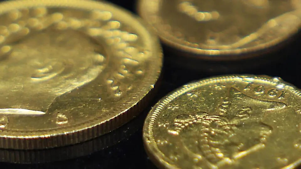 Moedas de ouro em cima de uma superfície preta.