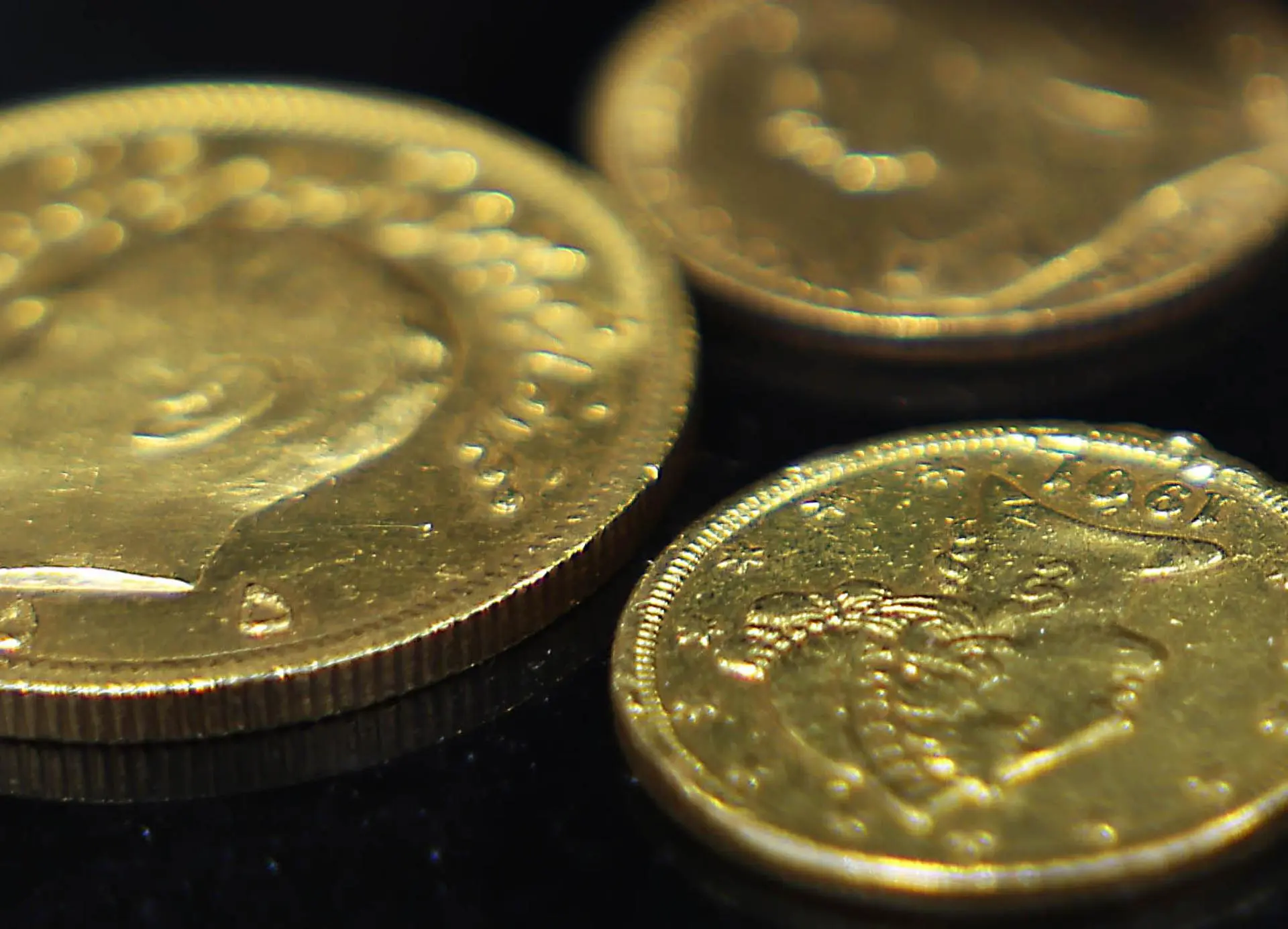 Moedas de ouro em cima de uma superfície preta.
