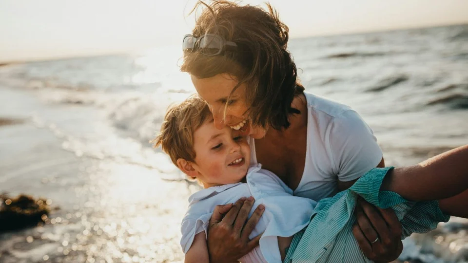 Mãe segurando o filho na praia.