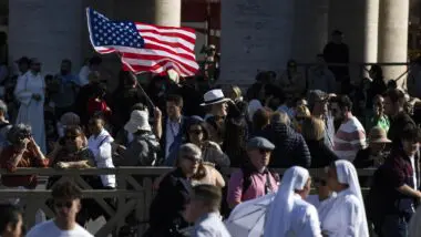 Fiel agita uma bandeira dos EUA na Praça de São Pedro, Cidade do Vaticano, em 8 de maio de 2025