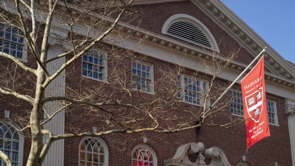 Bandeira de Harvard tremula do lado de fora do Lehman Hall, no campus em Cambridge, Massachusetts, EUA, em 3 de janeiro de 2024: Harvard adota políticas de contratação com foco racial, potencialmente violando a legislação de direitos civis dos EUA