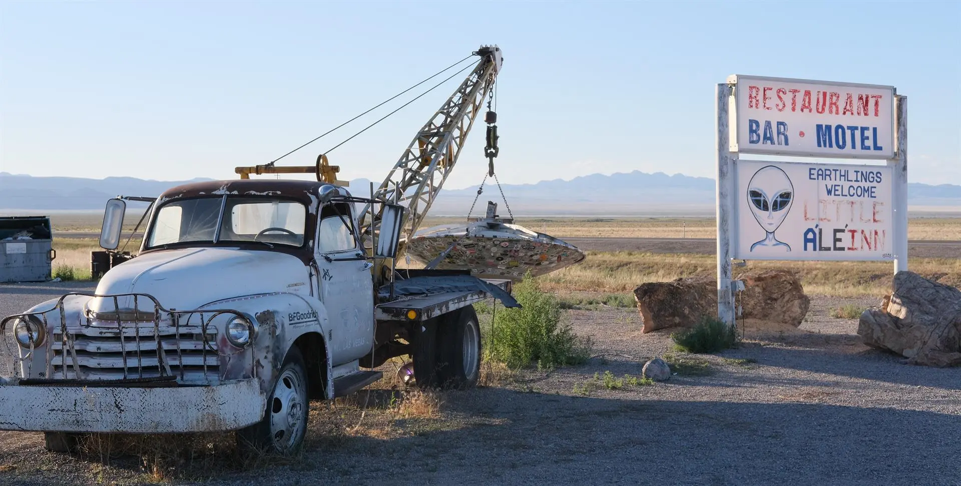Uma caminhonete antiga ao lado de uma placa de hotel, na Área 51.