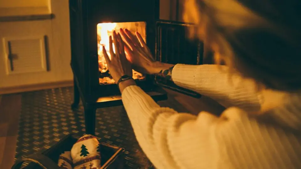 Frente fria se aproxima do Sul do país. A imagem trás uma mulher esquentando as mãos em uma lareira.