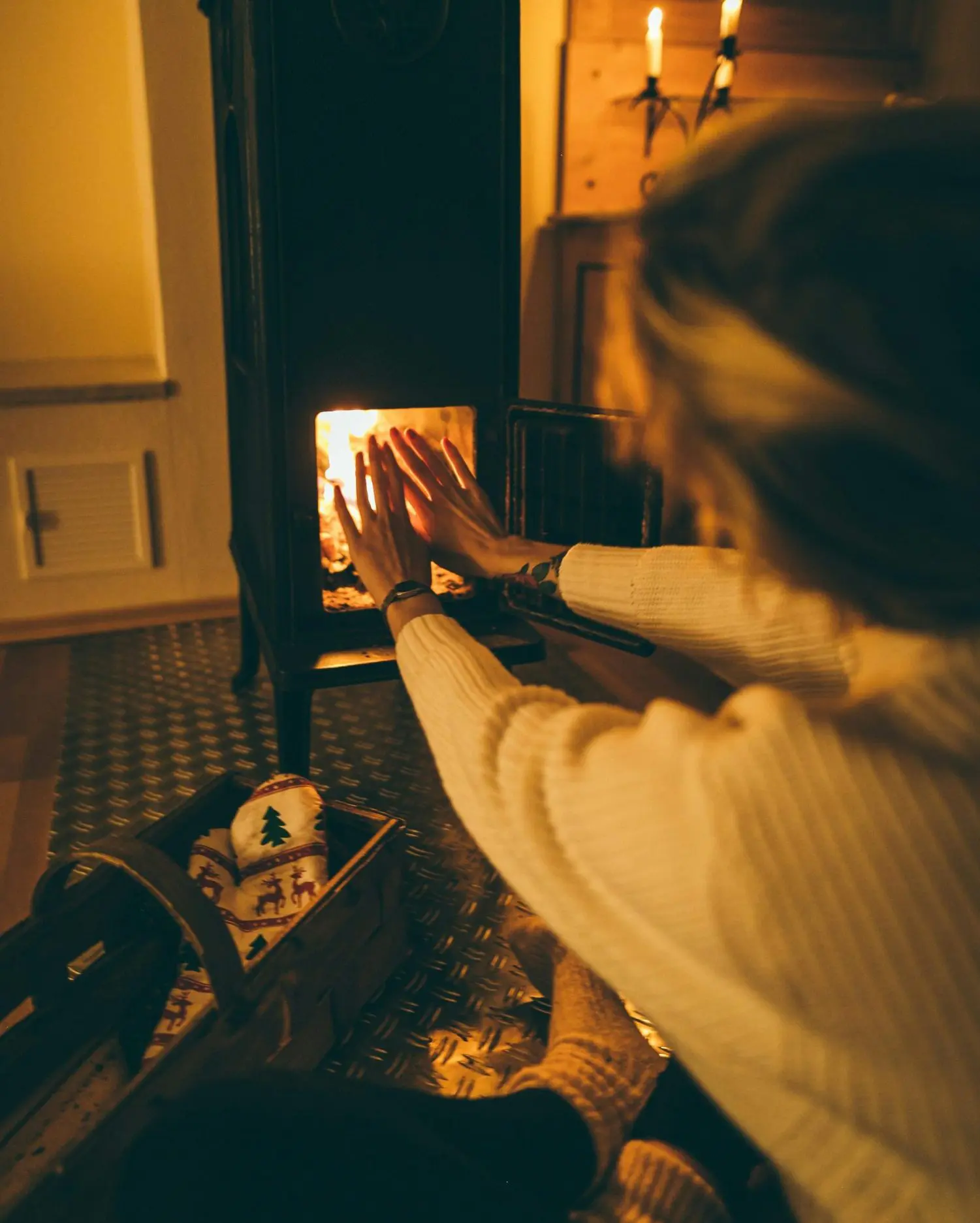 Frente fria se aproxima do Sul do país. A imagem trás uma mulher esquentando as mãos em uma lareira.