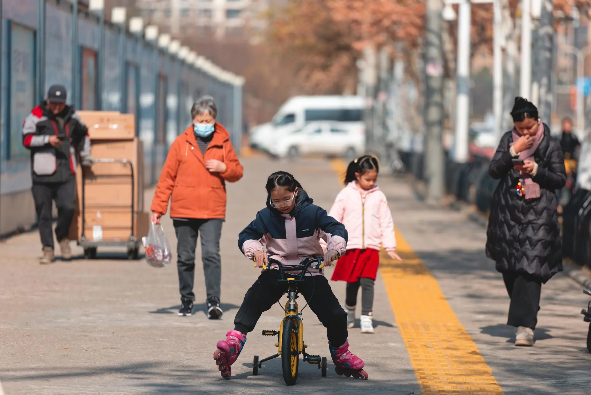 Pessoas caminham em frente ao Mercado de Frutos do Mar de Huanan, fechado e cercado, em Wuhan, província de Hubei, China, 20 de janeiro de 2025. O mercado de frutos do mar de Huanan, suspeito de ser uma fonte potencial do vírus, permanece fechado, com guardas de segurança ainda posicionados do lado de fora. A OMS estima quase 800 milhões de infecções e sete milhões de mortes, embora os números variem.