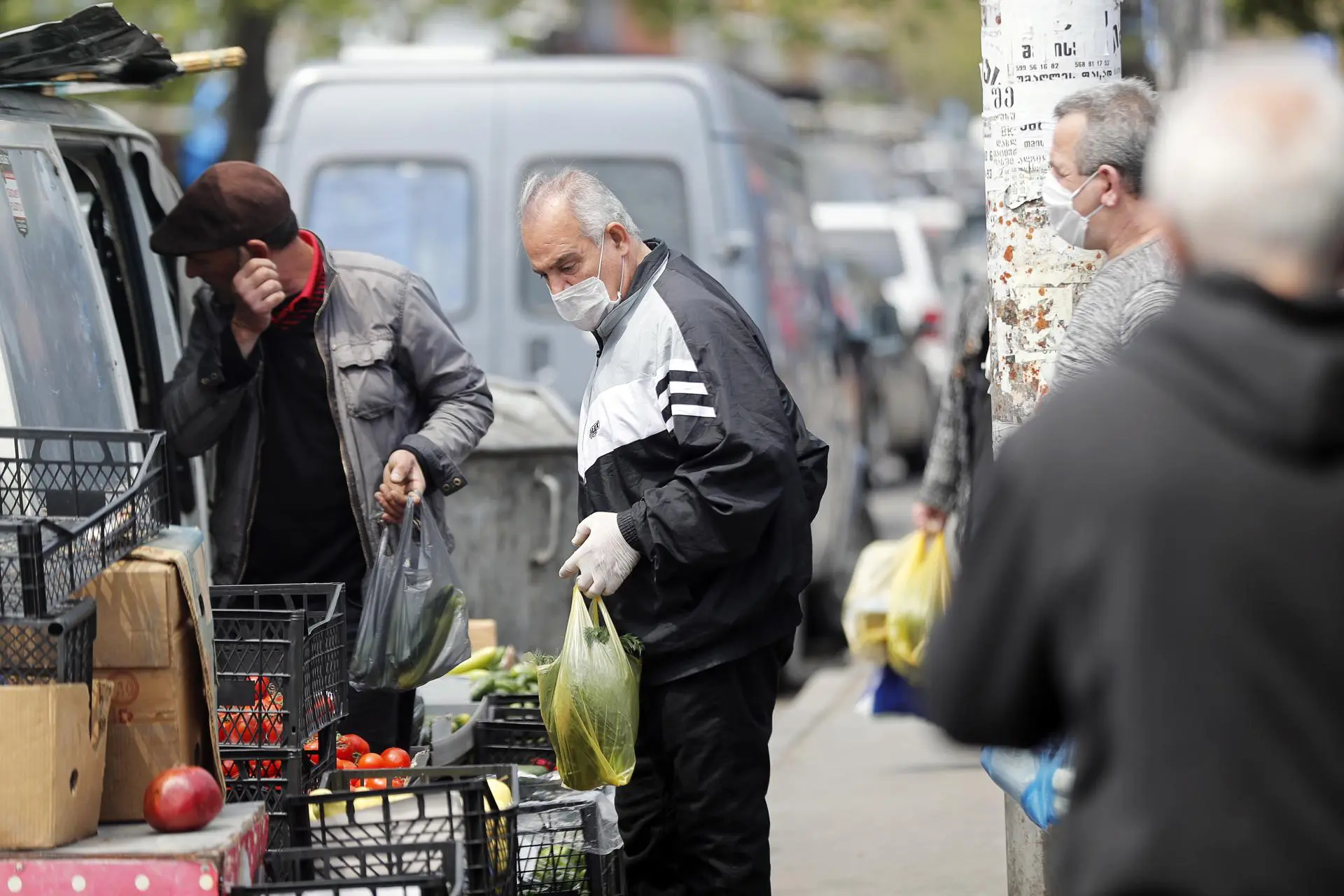 Pessoas usam máscaras de proteção em um mercado de rua em Tbilisi, Geórgia, em 27 de abril de 2020: durante a pandemia de COVID-19, enquanto lockdowns e toques de recolher afetavam os pequenos negócios em toda a Europa, trabalhadores informais georgianos se reinventaram.