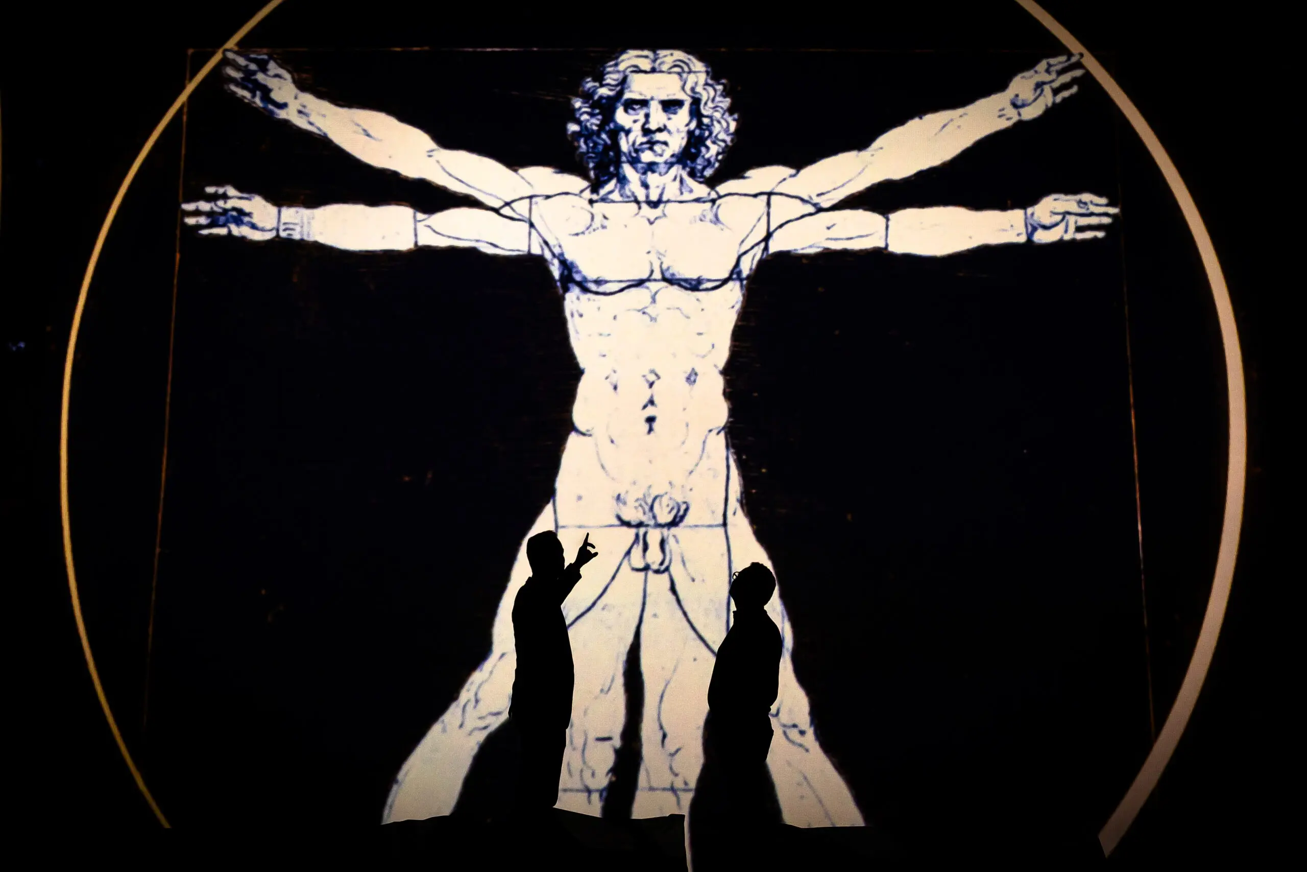Pessoas são vistas em silhueta diante do Homem Vitruviano durante a prévia da exposição imersiva 'Leonardo Da Vinci – Uomo Universale' no Maag Hall, em Zurique, Suíça, em 24 de abril de 2024.