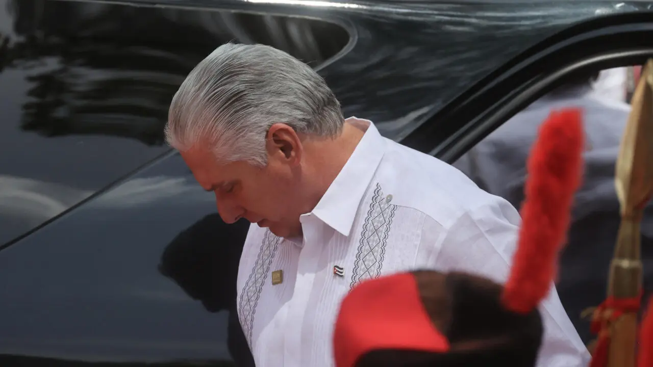 Imagem de Donald Trump discursando com expressão firme, ao lado de Miguel Díaz-Canel com rosto tenso, sobreposto com bandeira cubana rasgada, porta-aviões americano e povo nas ruas