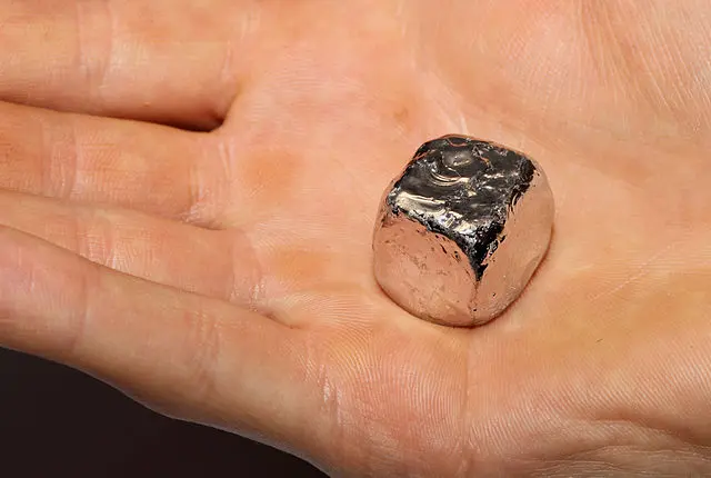 Mão de uma pessoa pegando o metal mais caro do mundo, o Ródio.