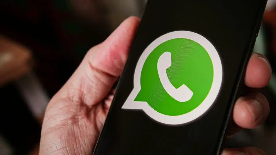 Pessoa segurando um celular aberto na página inicial do WhatsApp.