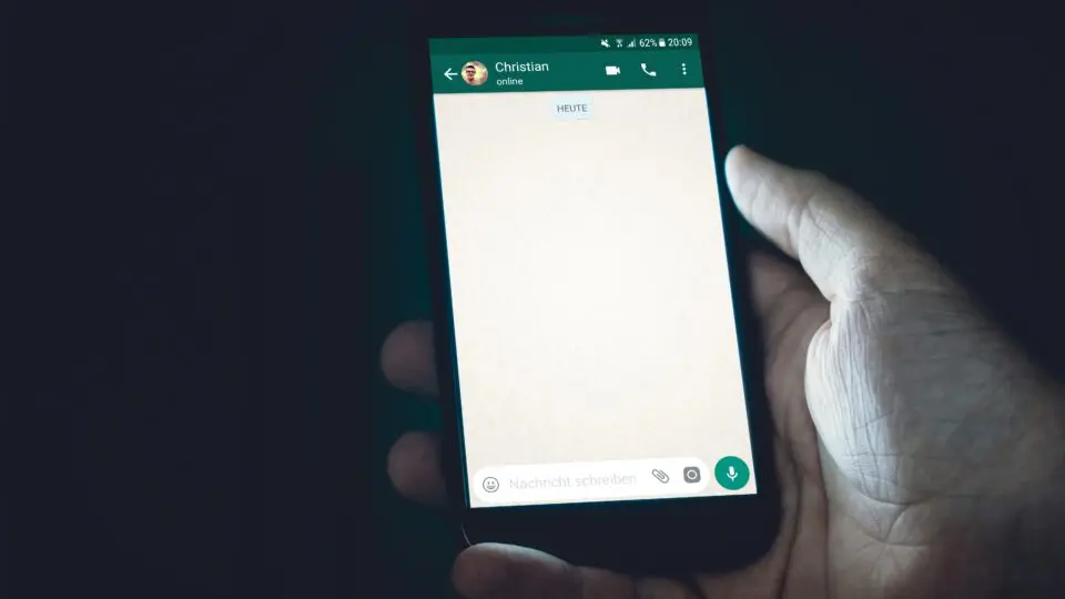 Pessoa segurando um celular com o WhatsApp aberto em uma conversa.