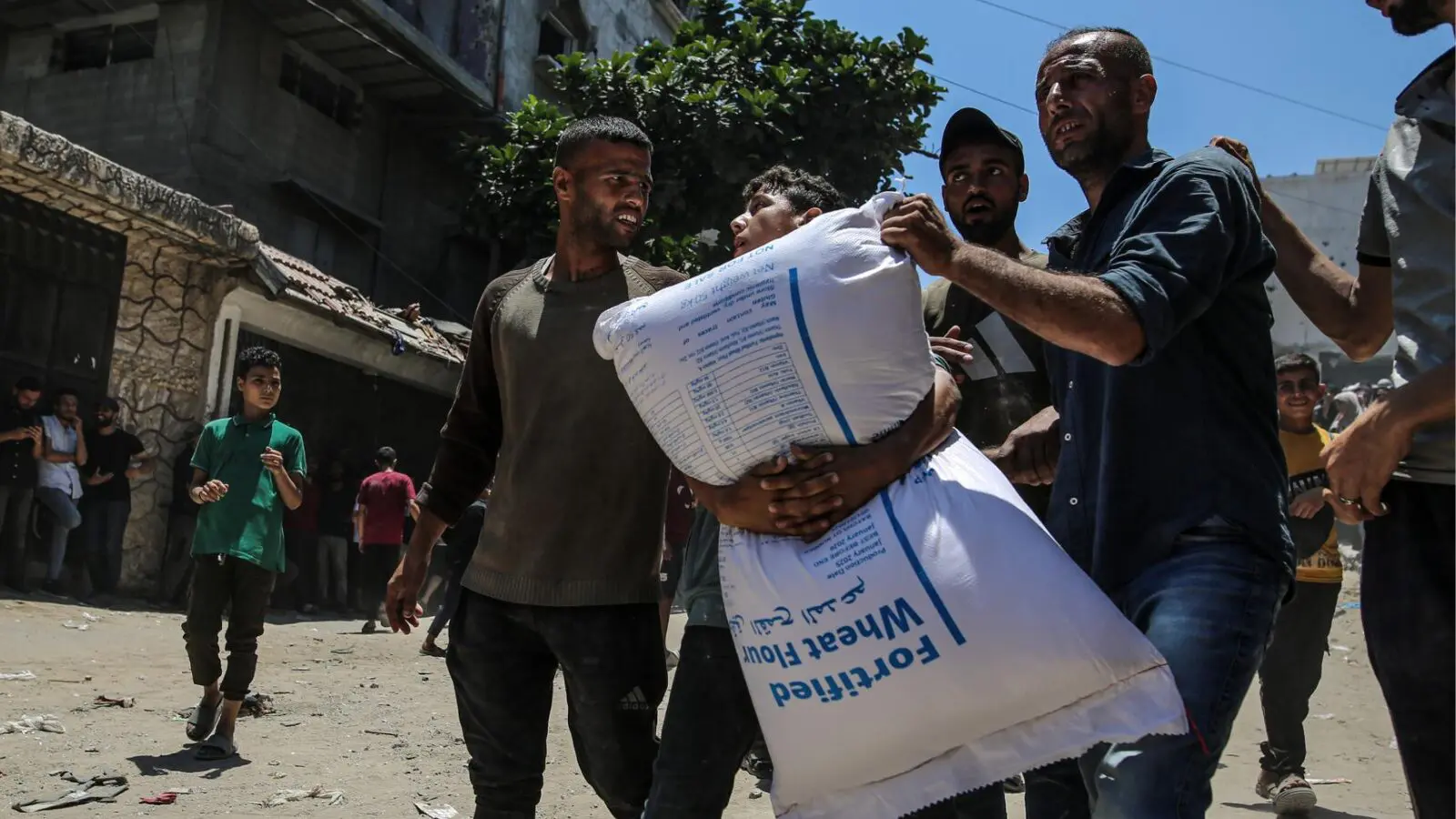 Moradores de Gaza carregam alimento distribuído em junho deste ano: Israel nega fome.