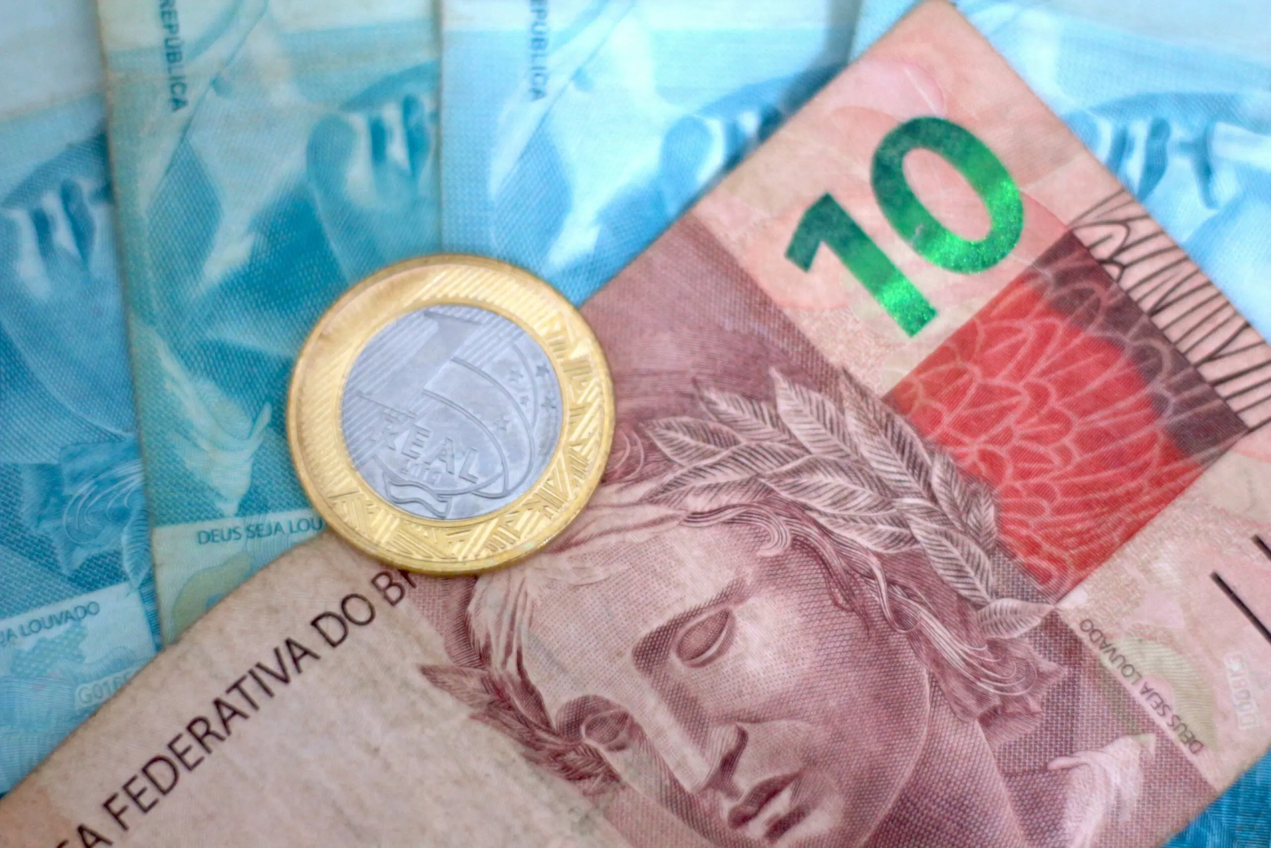 Ein Zehn-Real-Schein neben mehreren Hundert-Real-Scheinen, darauf eine Ein-Real-Münze, die zum vergessenen Geld des Values Receivable System gehören.