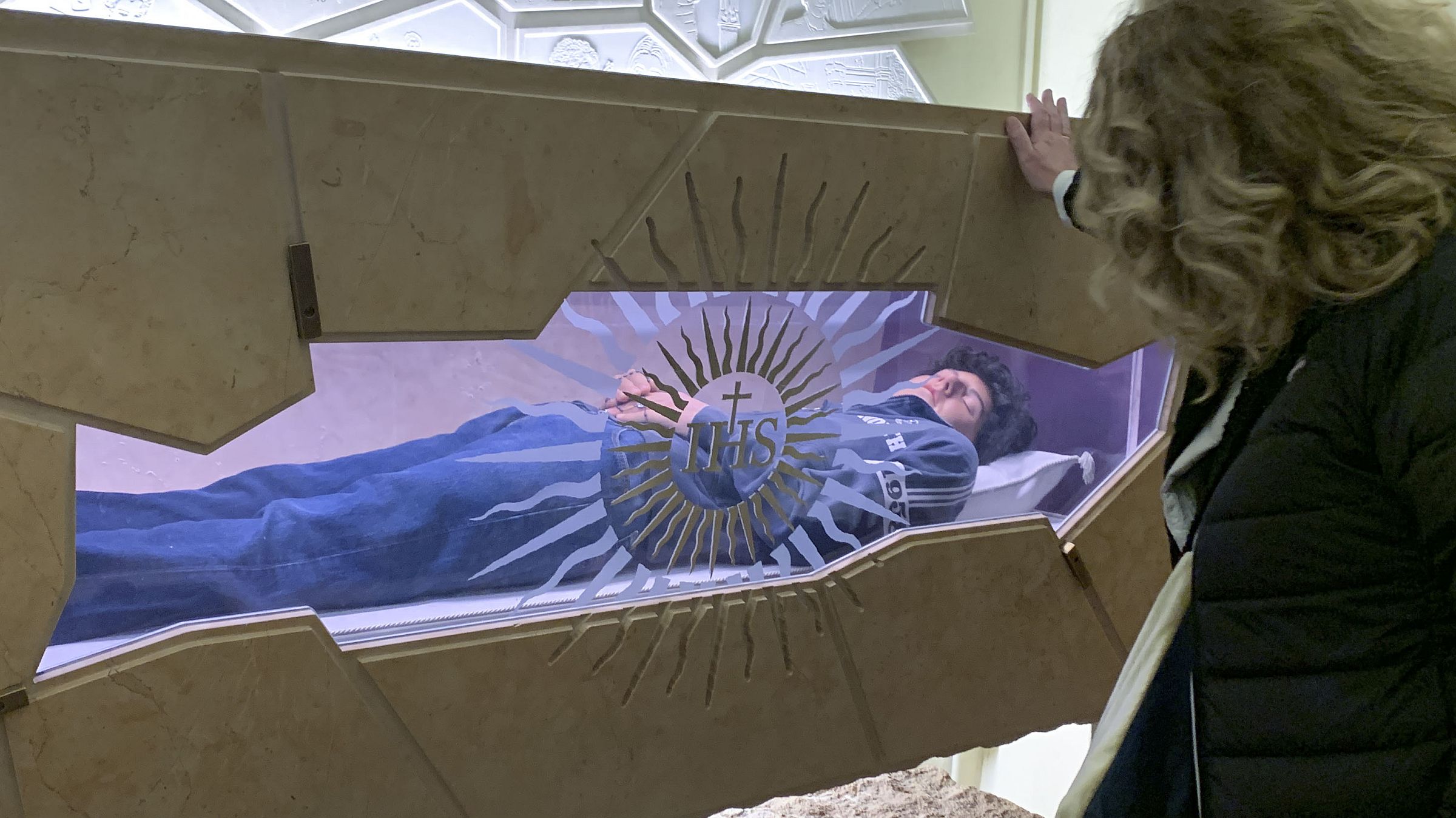 Devota diante do corpo de Carlo Acutis, em exposição na cidade de Assis, em abril de 2025.